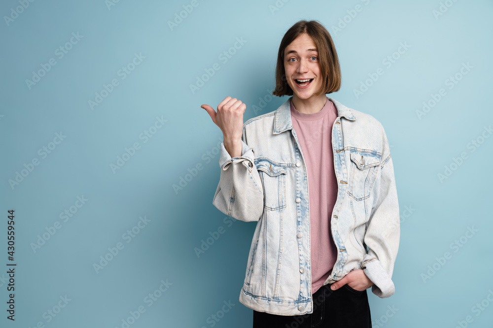 Young european man smiling and pointing finger aside Young european man smiling and pointing finger aside