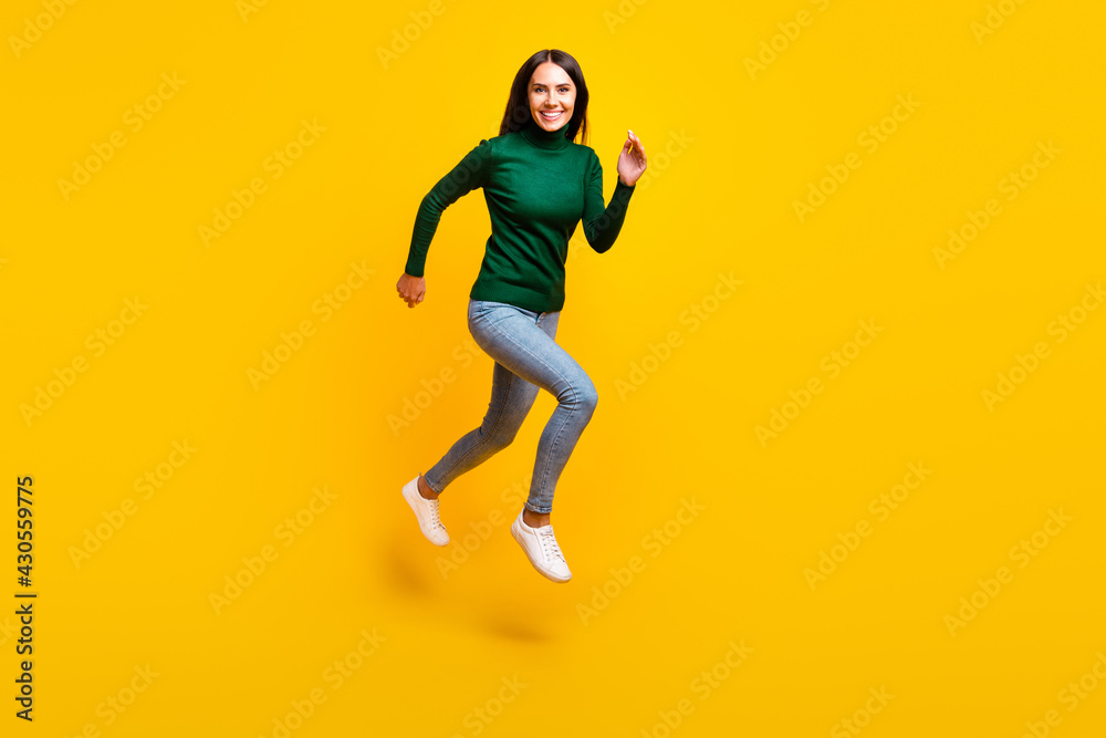Full size photo of nice optimistic brunette lady jump wear green sweater jeans sneakers isolated on bright yellow color background