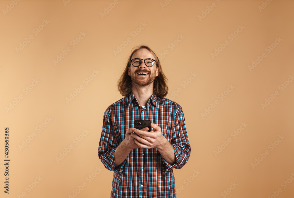 White ginger man wearing eyeglasses smiling and using cellphone White ginger man wearing eyeglasses smiling and using cellphone