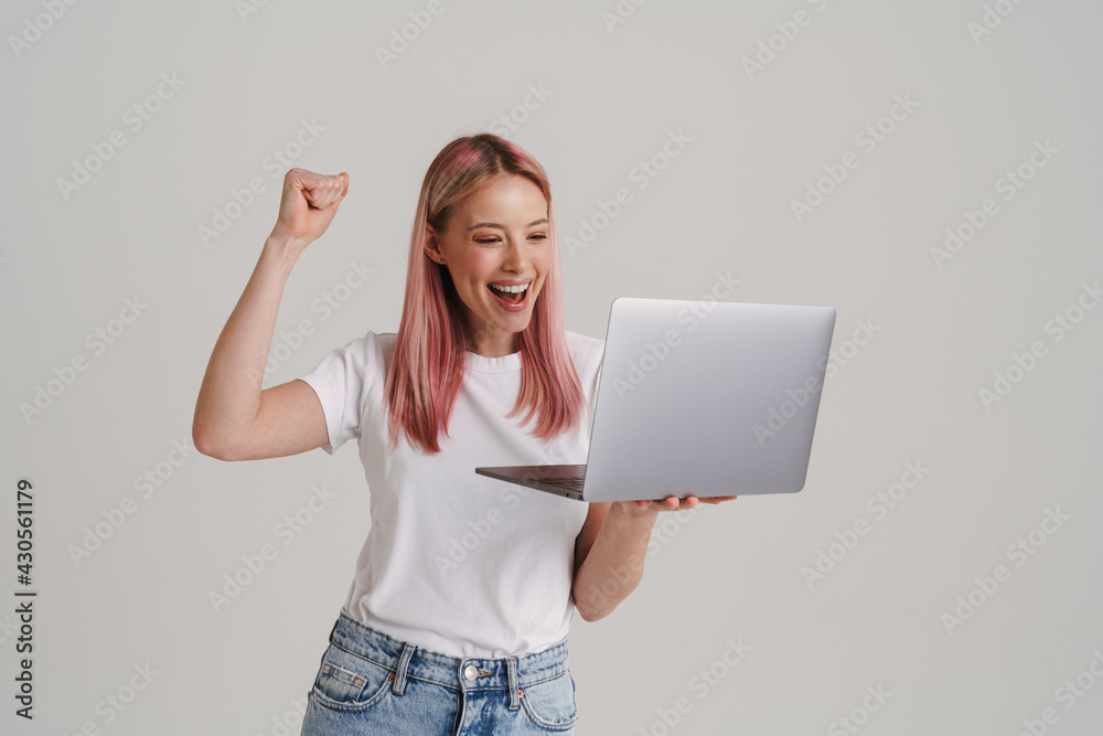 Excited european woman making winner gesture while holding laptop Excited european woman making winner gesture while holding laptop
