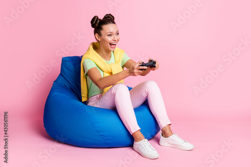 Photo of funny sweet woman wear green t-shirt sitting beanbag playstation looking empty space isolated pink color background