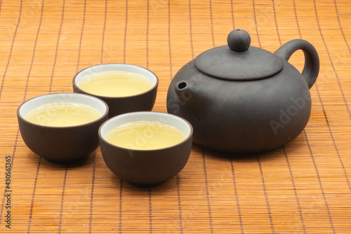pottery Chinese teapot and teacup with tea on bamboo mat