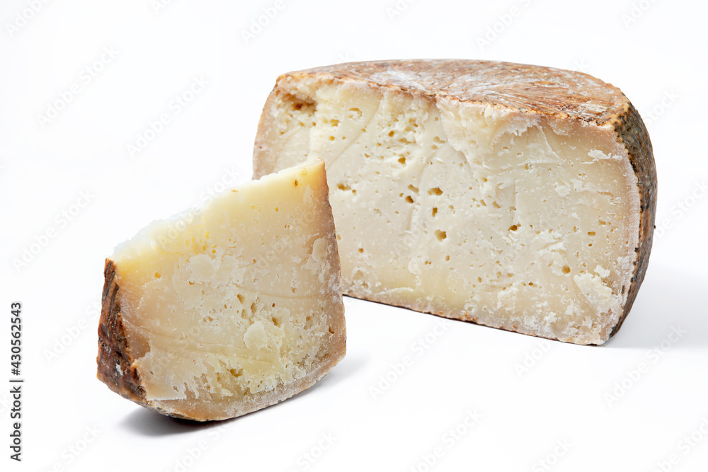 a piece of aged pecorino cheese with cheese wheel in white background