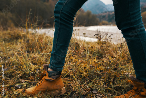 female legs in boots and jeans on nature in autumn in the mountains