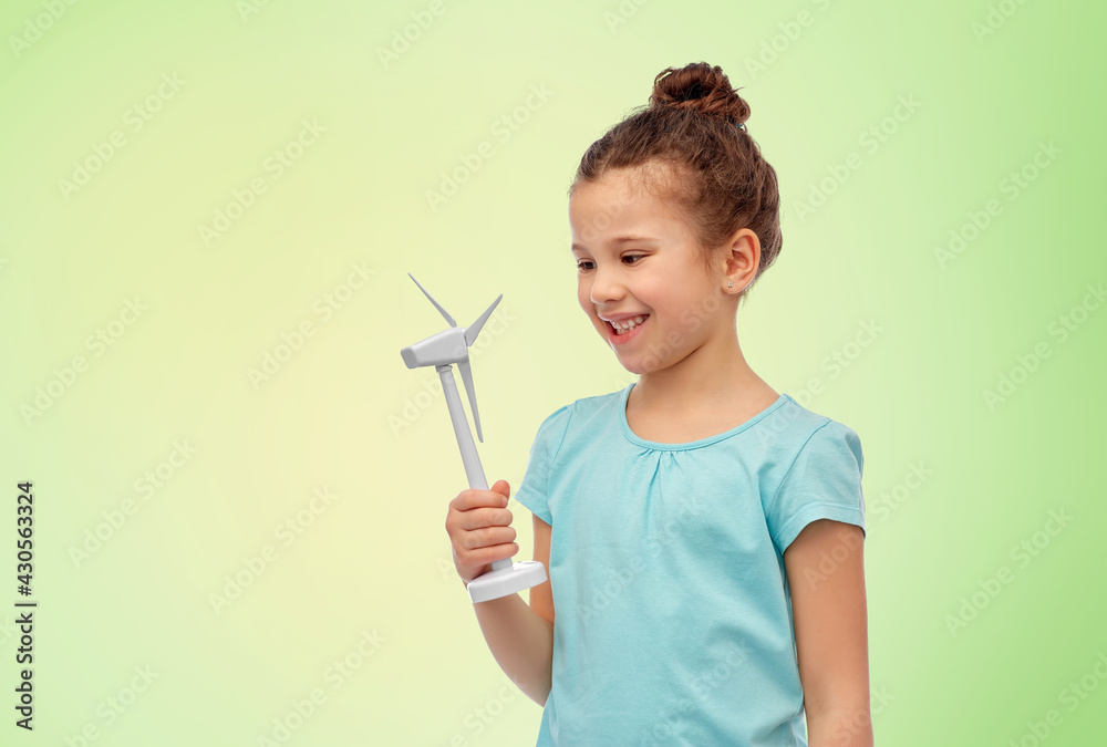 sustainable energy, power and people concept - happy smiling girl with toy wind turbine over green background sustainable energy, power and people concept - happy smiling girl with toy wind turbine over green background