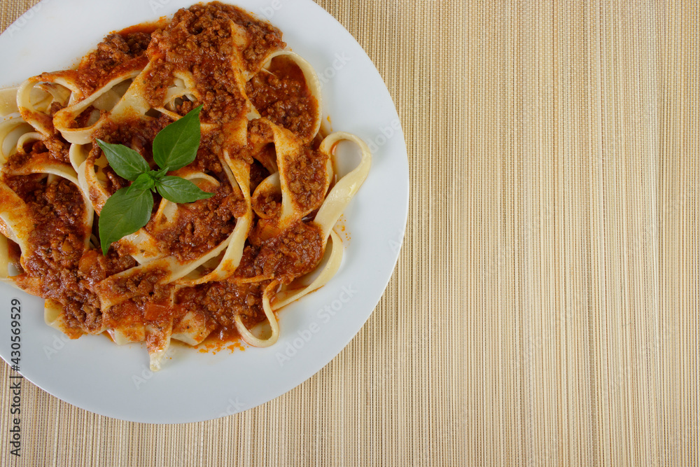 Tasty Pasta with bolognese sauce and basil leaves. Photograph of Italian noodles. Close-up photo of top view with space for text on the right. Tasty Pasta with bolognese sauce and basil leaves. Photograph of Italian noodles. Close-up photo of top view with space for text on the right.