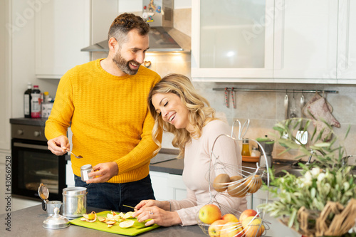 Happy couple in the kitchen. Romantic young couple preparing fresh fruit and coffee. Healthy life and love. Smiling people living together.