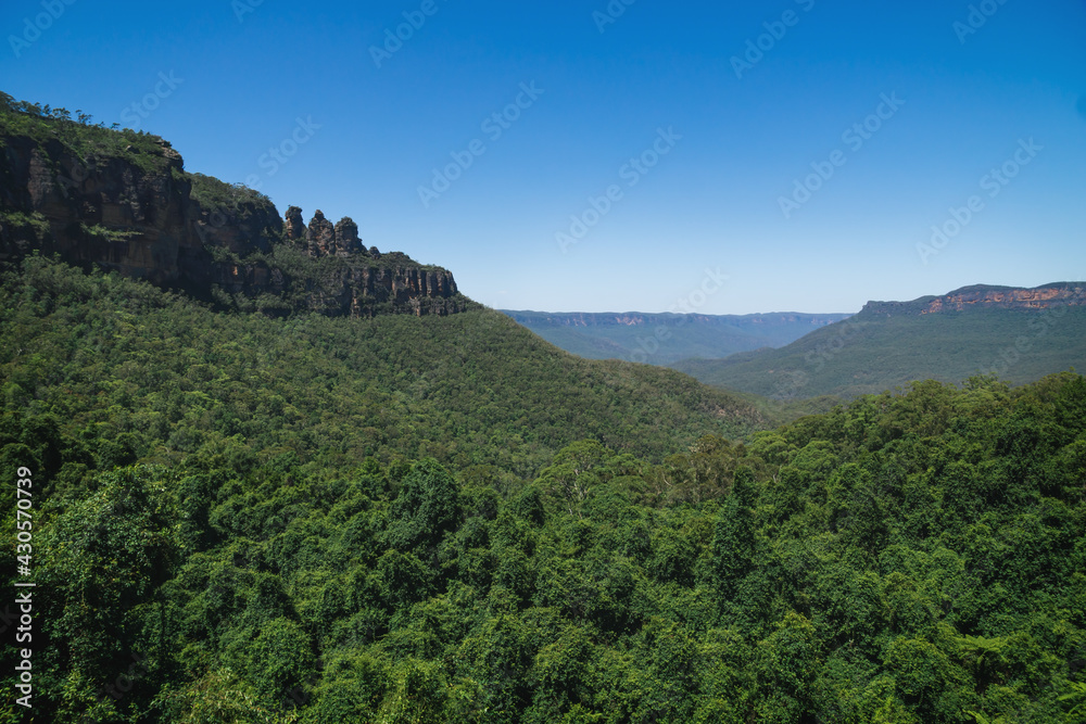View into green forest valley with the rock formation 'Three Sisters' in the Blue Mountains, Australia