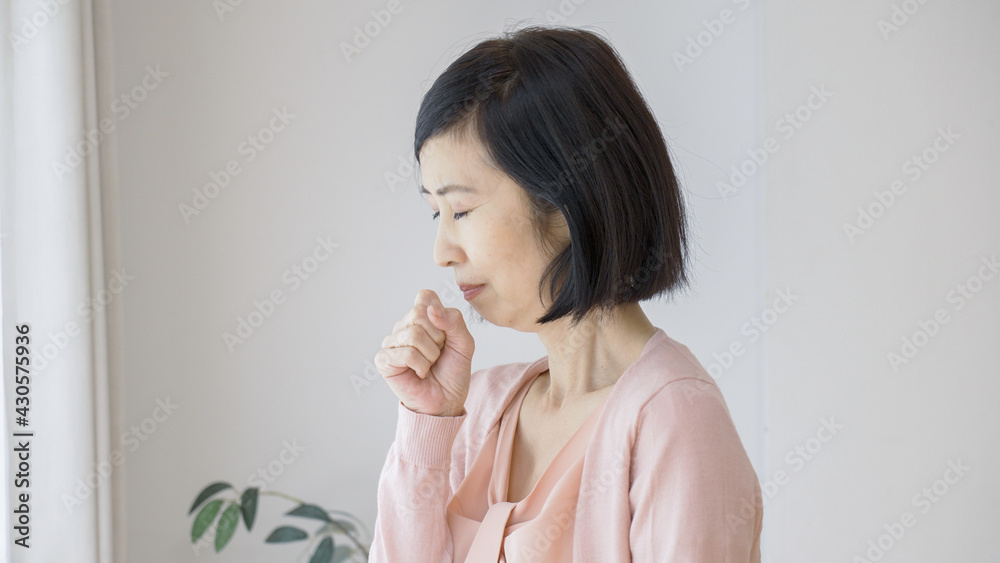 喉が痛くて咳をするシニア女性 喉が痛くて咳をするシニア女性