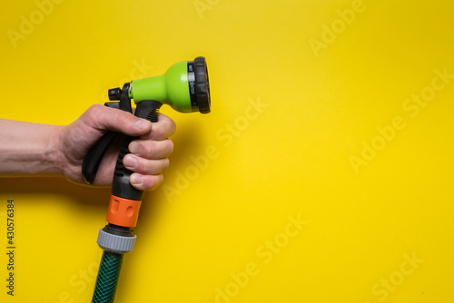 Gardening sprinkler with a water hose in gardener hand on the yellow flat lay background with copy space. photo