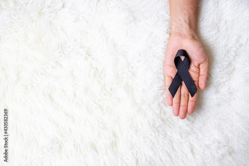 Melanoma and skin cancer, Vaccine injury awareness month and rest in peace concepts. Man holding black Ribbon on white bed background