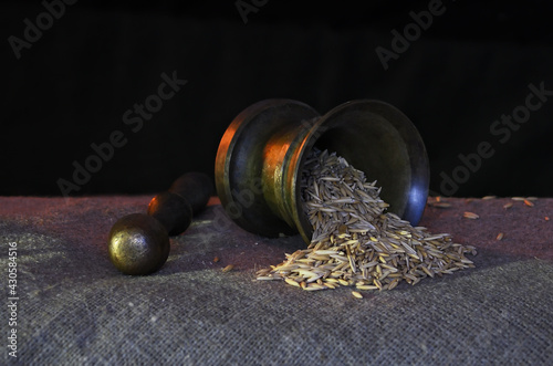 Still life in a warm light with the mortar and the pestle with scattered grains of oats