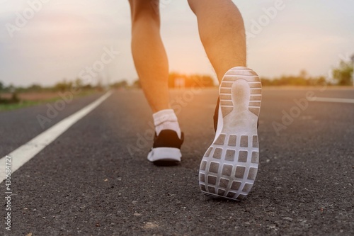 Running feet on road with sunset - healthy concept