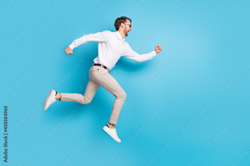 Full size profile side photo of happy amazed young man run jump up empty space sale isolated on blue color background
