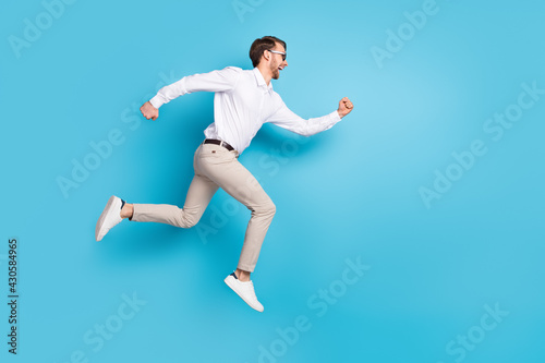Full size profile side photo of happy amazed young man run jump up empty space sale isolated on blue color background