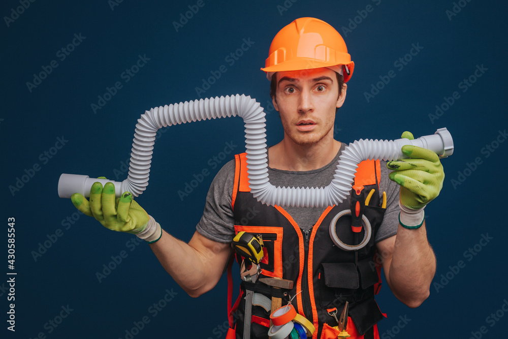 Fototapeta premium Curious builder is having trumpet in arm, isolated over blue background