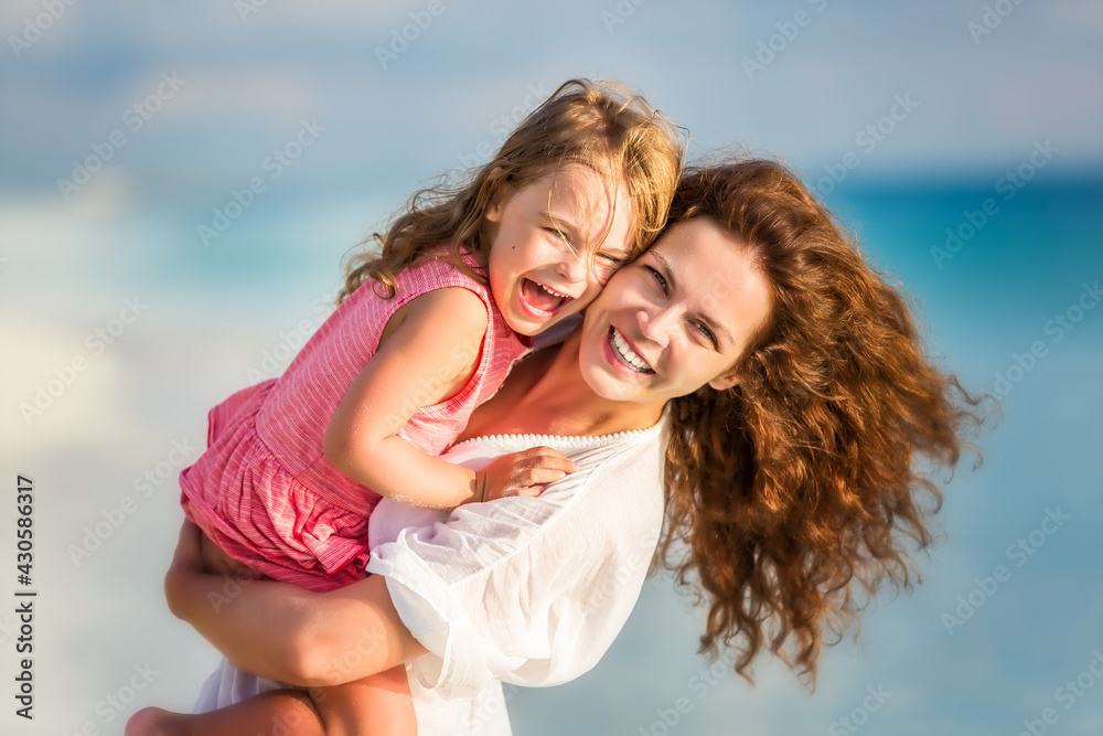 Portrait of happy mother and little daughter on sunny beach on Maldives at summer vacation Portrait of happy mother and little daughter on sunny beach on Maldives at summer vacation