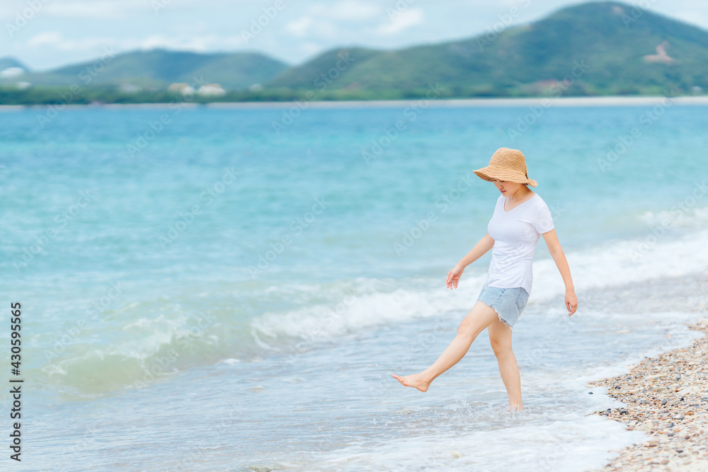 Island and beautiful blue sea in front of woman wearing white shirt and hat at Kham Island, Sattahip, Chon Buri, Thailand.