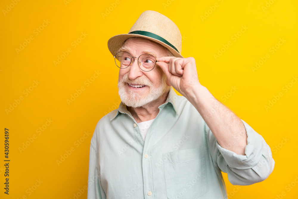 Photo of excited sweet age gentleman wear green shirt arm spectacles headwear looking empty space isolated yellow color background