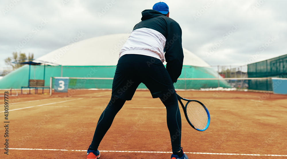 Obraz premium A professional male tennis player waiting to hit during a game. Young athlete man playing tennis on the court outdoors.