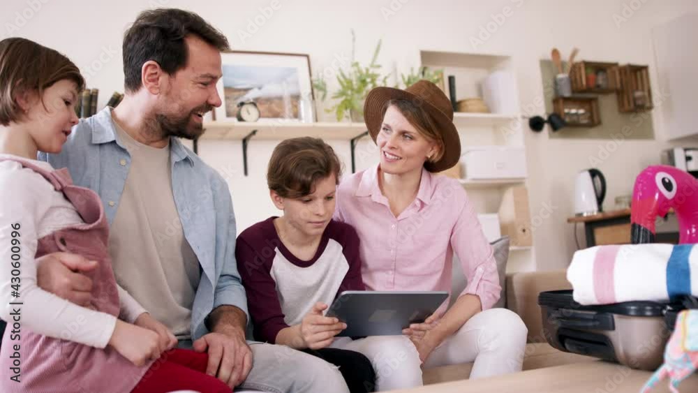 Beautiful family packing, making preparations for vacation on tablet. Beautiful family packing, making preparations for vacation on tablet.
