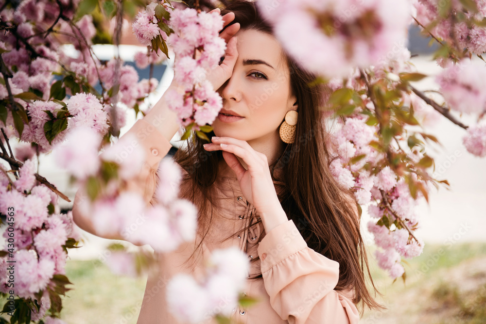 Fototapeta premium Girl in park under blossom sakura tree flowers