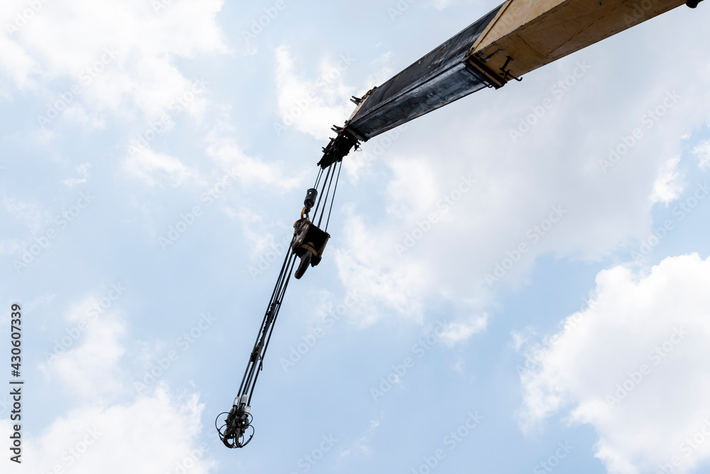 Yellow crane boom with hooks and blue sky background Yellow crane boom with hooks and blue sky background