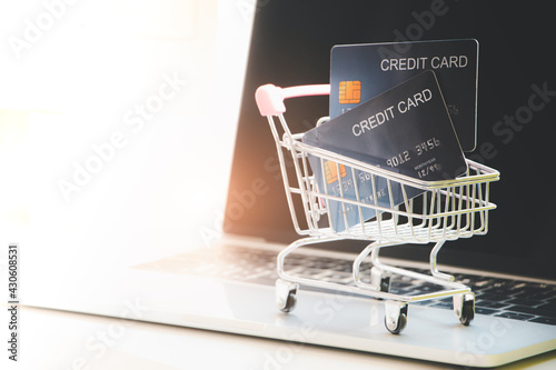 Credit card in shopping cart model on laptop. Concept and Idea of online shopping and payment with credit card (Cashless). Free copy space on left for text or design