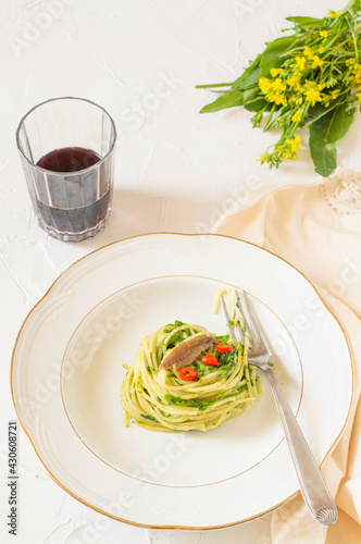 Typical italina dish: spaghetti with broccoli, anchovies and red pepper. White background and fresh broccoli flowers on back. photo