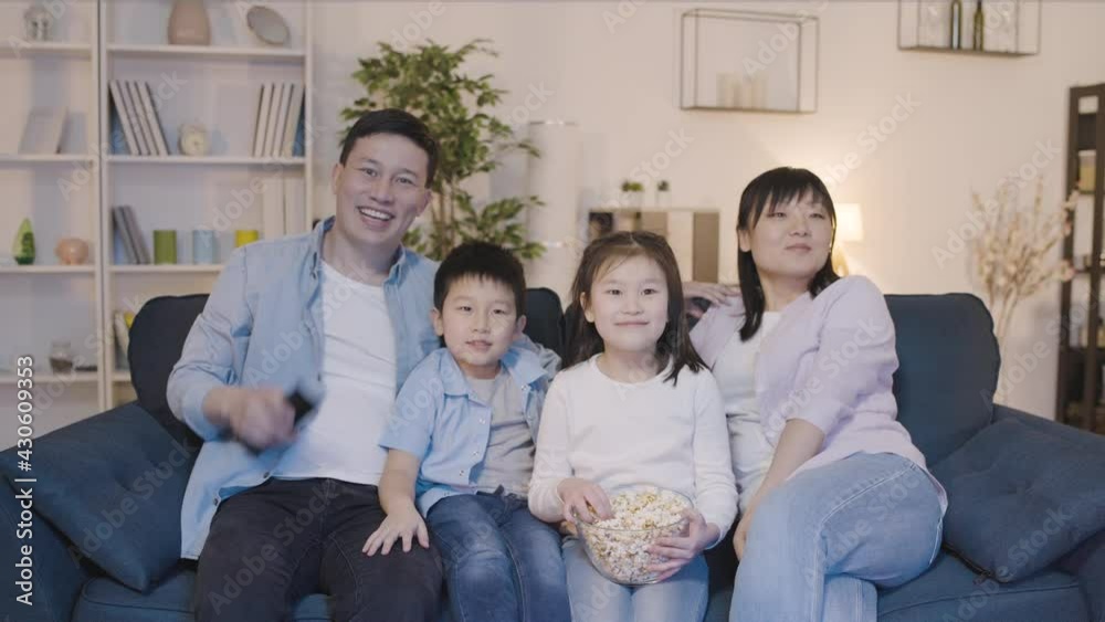 Nice asian family watching tv and eating popcorn on couch home, happy together Nice asian family watching tv and eating popcorn on couch home, happy together