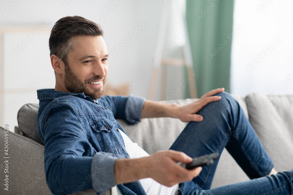 Fototapeta premium Relaxed bearded man switching channels on TV