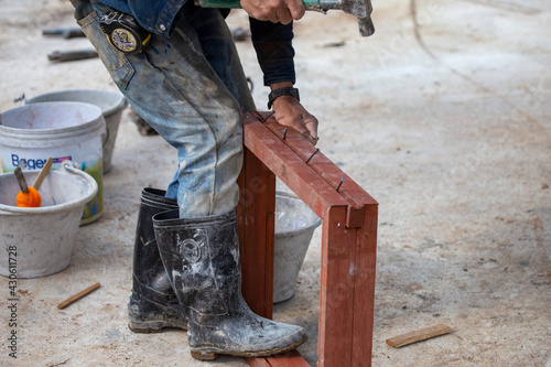 The wooden window is a rectangular frame and the construction workers. Nails are being hammered so that the nailed part is fixed to the mortar of the wall. To make a house window structure