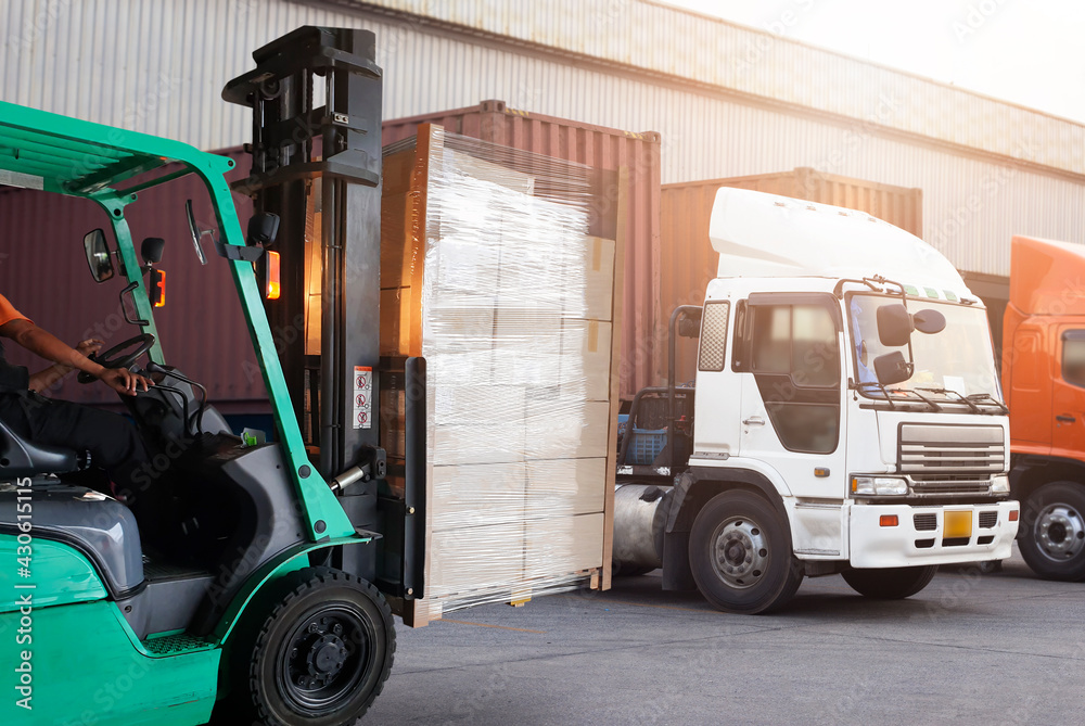 Forklift Driver Loading Package Boxes. Trailer Trucks Parked Loading at Dock Warehouse. Shipment Delivery Service. Shipping Warehouse Logistics. Freight Truck Transportation.	