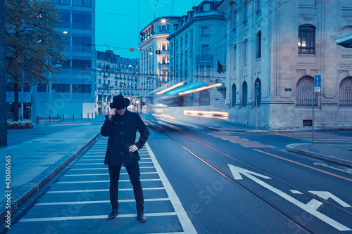 Cityscape of Geneva downtown in Quartier des Banques district in early morning at blue hour, with a men in black wearing a fedora hat. photo