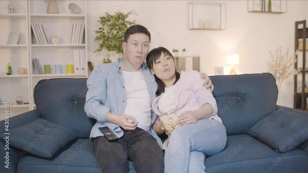 Happy asian couple sitting on couch watching tv home together, love relationship Happy asian couple sitting on couch watching tv home together, love relationship