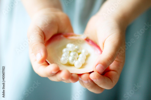 Children's hands hold oyster shell with pearls 