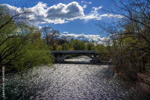 A bridge crosses the Boise River as green leaves and fluffy white clouds punctuate a beautiful spring day in Boise, Idaho.