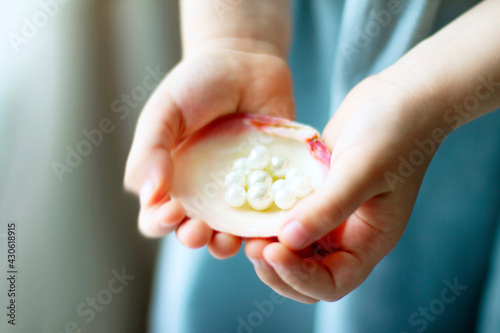 Children's hands hold oyster shell with pearls	