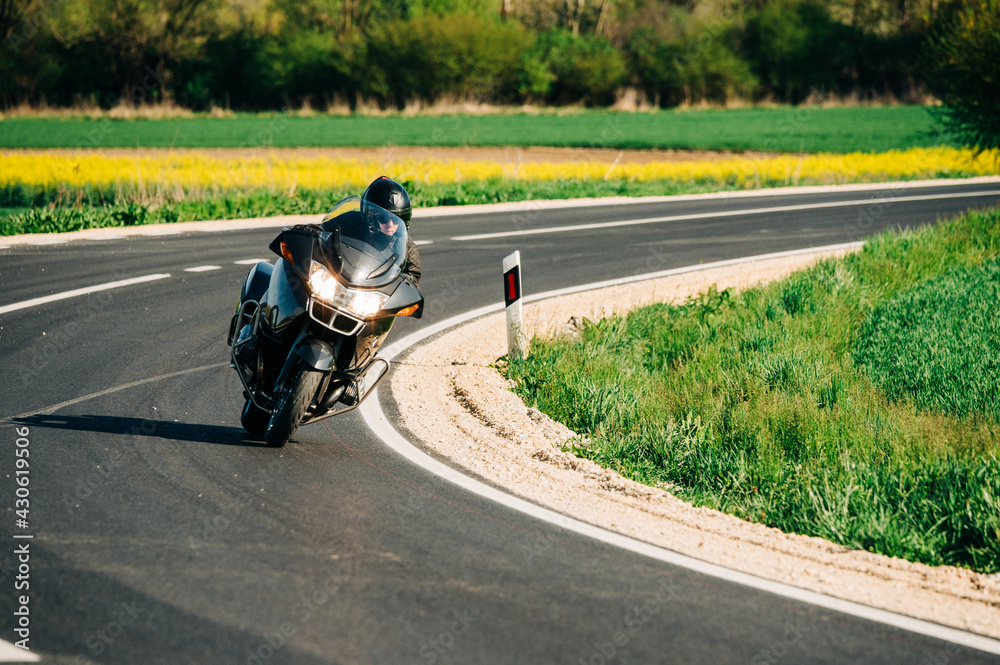 Motorcycle driver riding alone on the asphalt road. Lifestyle photo of a biker in the motion at the empty road