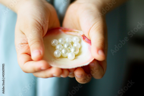Children's hands hold oyster shell with pearls	