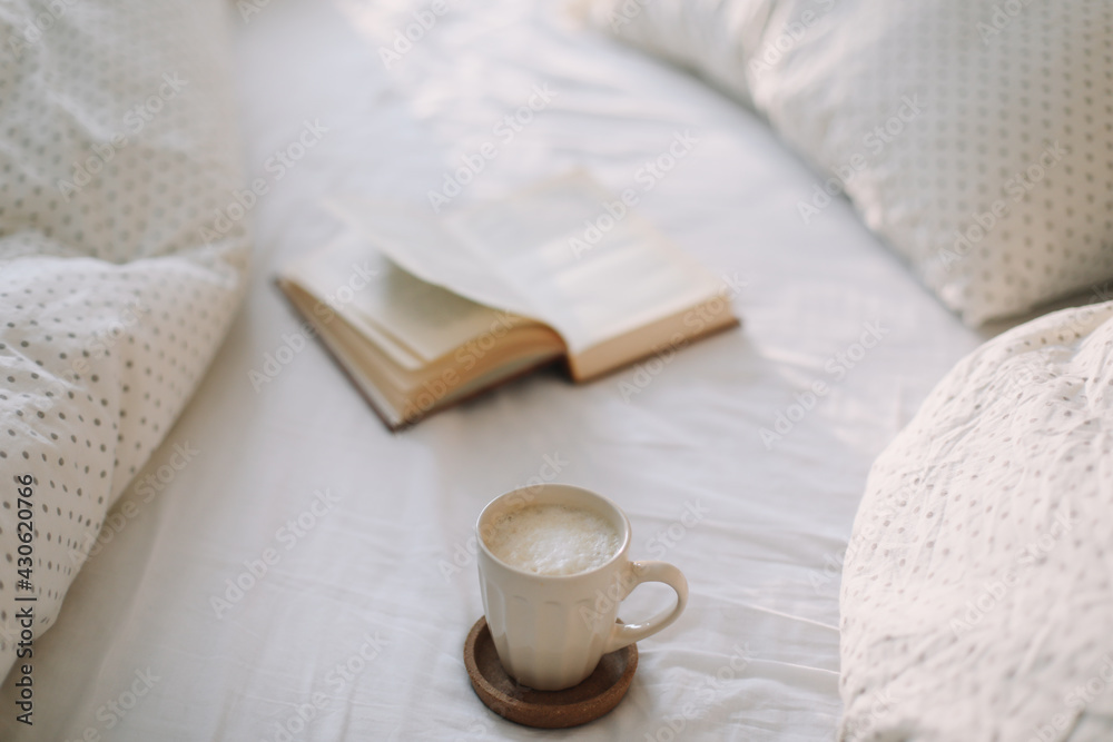 Open book on bedsheets and a cup of coffee. Good morning. Breakfast in bed. flat lay