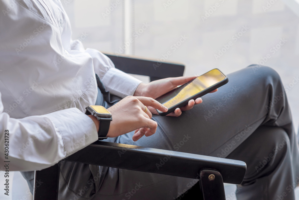 Close-up of a businesswoman hand sitting in a chair holding a smartphone at the office.