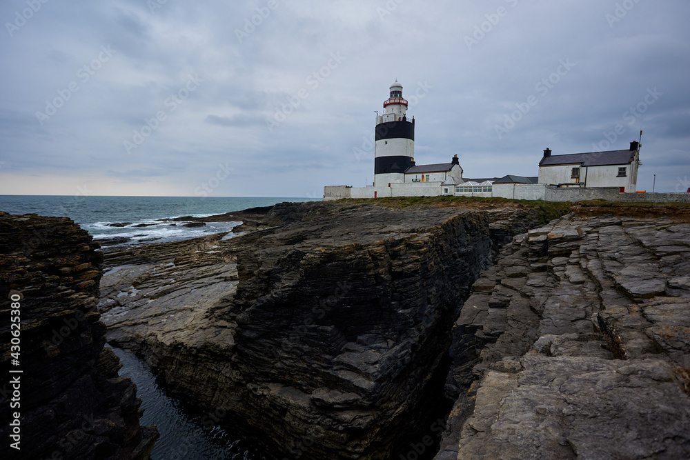 Hook Lighthouse landscape with cliffs and waves and peninsula Heritage center in Wexford, Ireland.