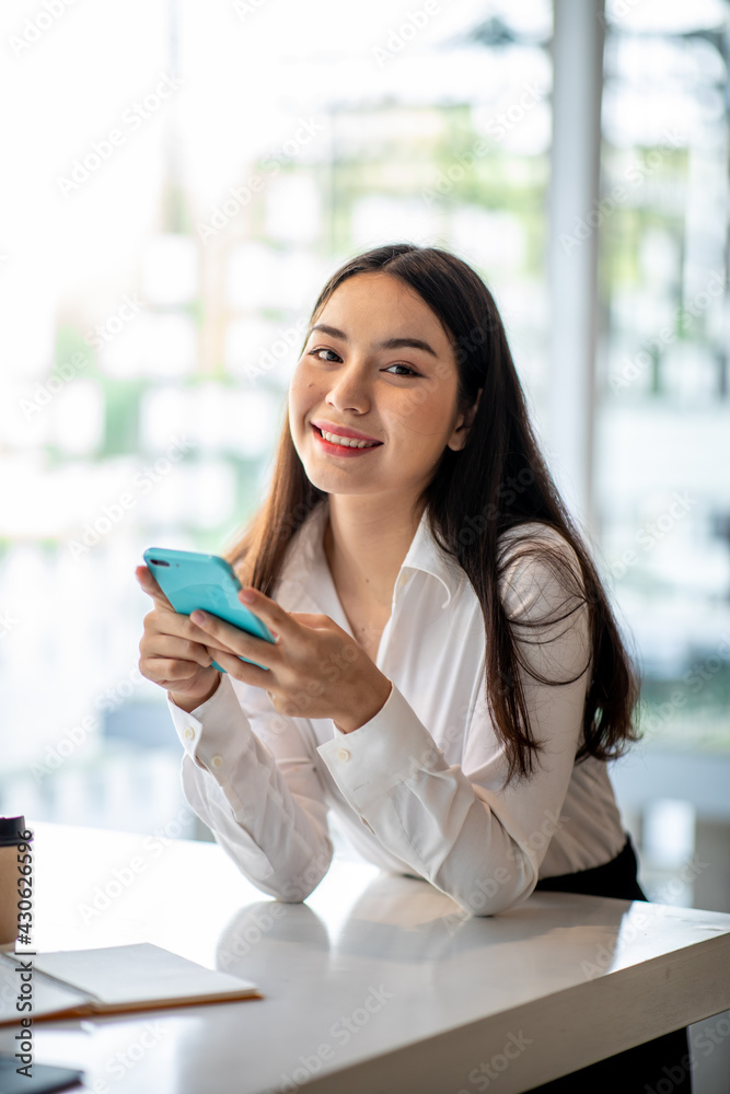 Obraz premium Young woman using smartphone at home. Student girl texting on mobile phone in her room. Communication, home work or study, connection, mobile apps, technology, lifestyle concept