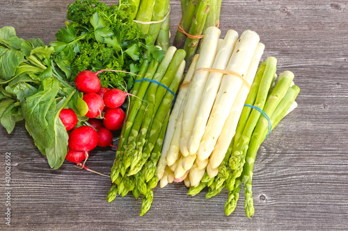 Grüne Spargel und weiße Spargel dekoriert auf einem rustikalen Holztisch