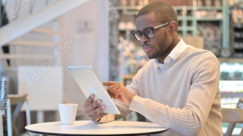 Serious Professional African Man using Tablet in Cafe 