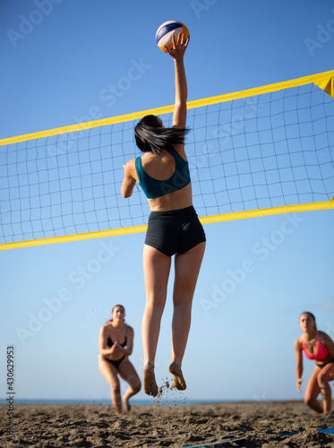 young women playing beach volleyball on a sunny day
