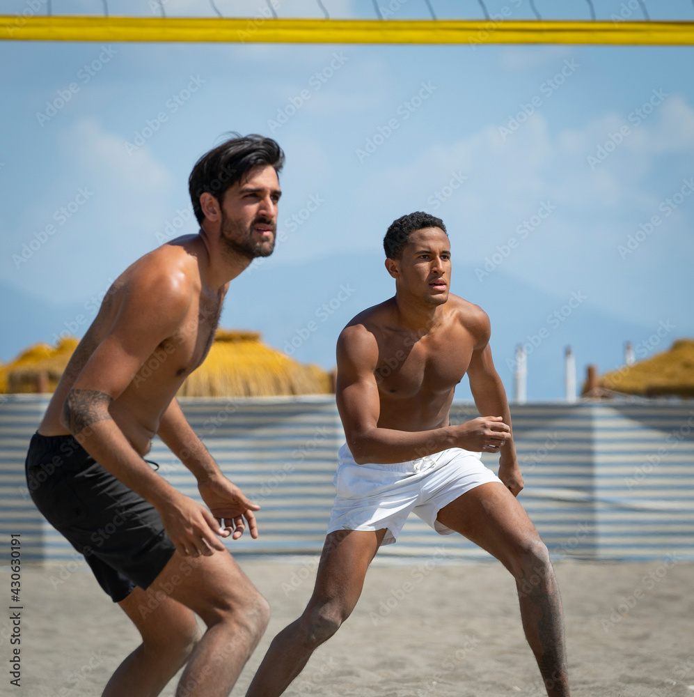 young men playing beach volleyball on a sunny day young men playing beach volleyball on a sunny day