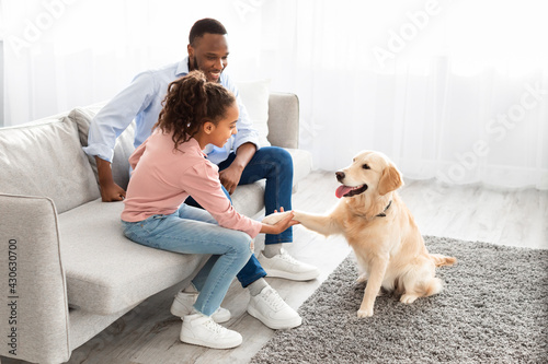 Smiling black girl playing with dog in the living room