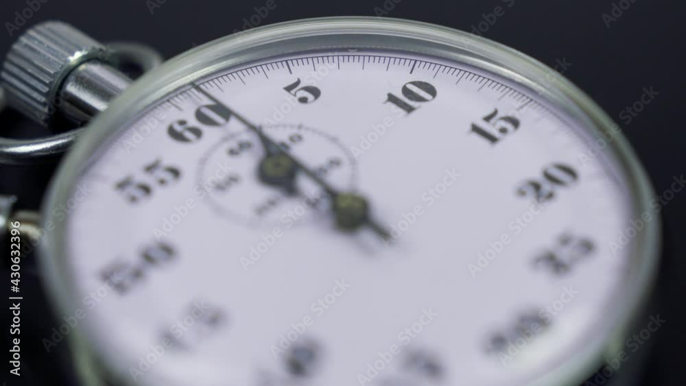 Macro shot of a classic metallic retro mechanical analog stopwatch against a dark background, counting down the seconds. Time management concept. Macro shot of a classic metallic retro mechanical analog stopwatch against a dark background, counting down the seconds. Time management concept.